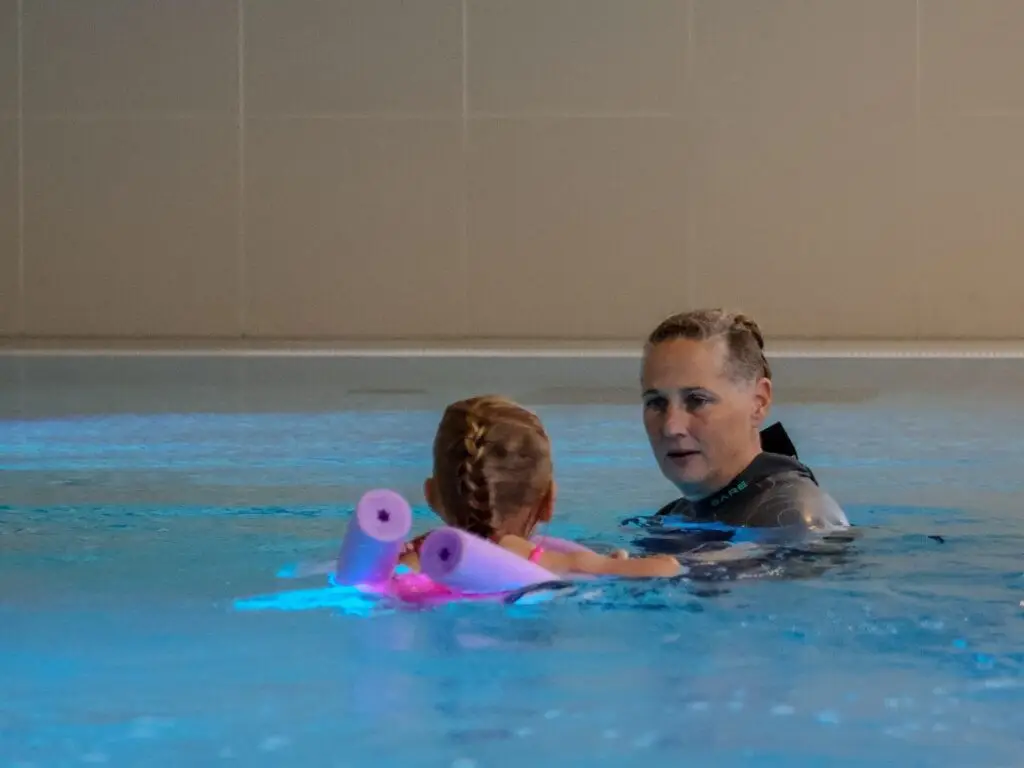 Kind oefent met drijfmiddelen samen met de zweminstructeur